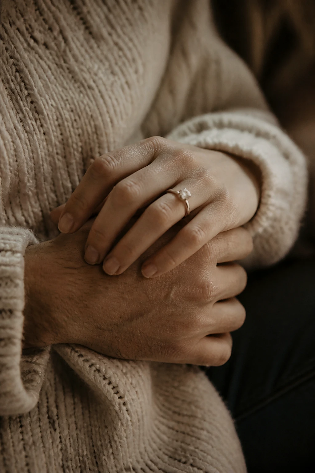 A couple's interlaced hands with an engagement ring